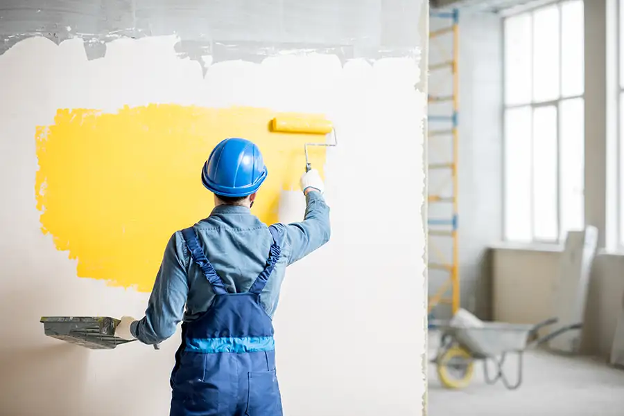 worker using paint roller to paint interior wall of commercial building yellow - Springfield, IL
