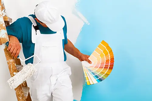 Golden Rule Handyman & Painting Service—A professional painter with a paint roller showing a color palette to paint the walls in a Springfield, IL home.