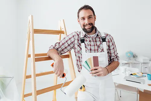 Golden Rule Handyman & Painting Service—A professional painter with a roller and paint colors next to a ladder inside a home in Springfield, IL.