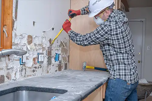 Golden Rule Painting & Handyman Service—A man using tools to remove tiles from a kitchen wall in a home in Springfield, IL.